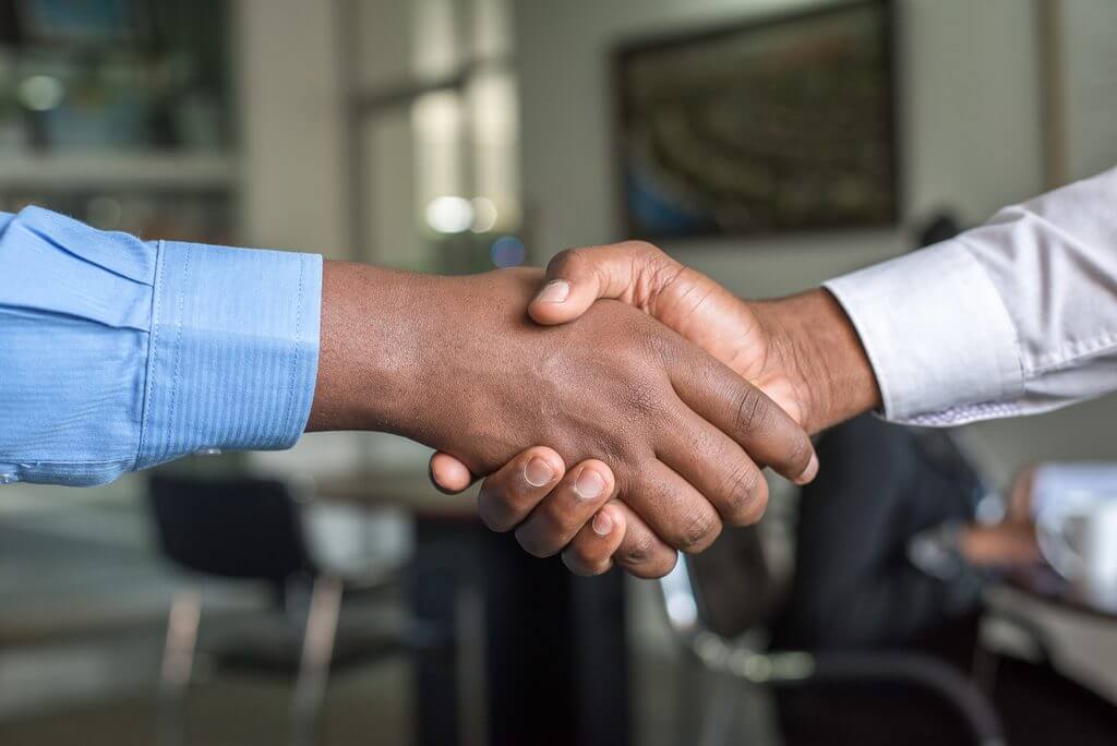 the wrists and hands of two people 'shaking hands'